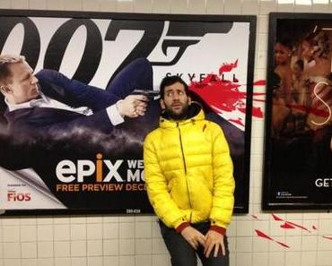 Künstler posiert neben Filmplakaten, um auf die dargestellte Gewalt hinzuweisen