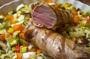 Im Ofen gegartes Schweinefilet im Speckmantel auf Gemüsebett